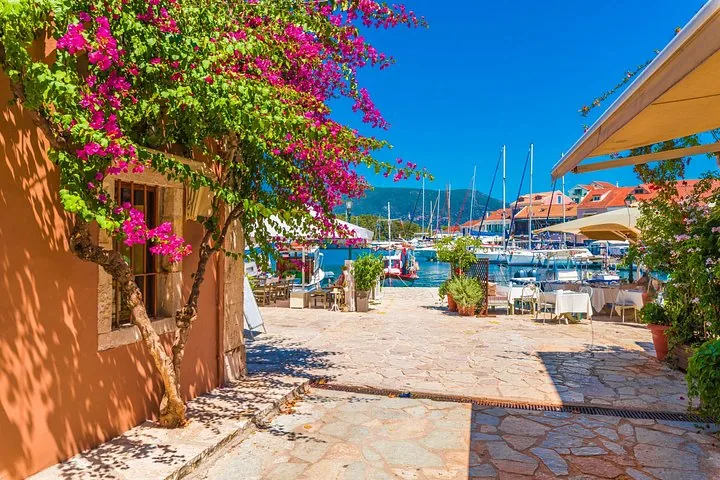 Charming Greek harbor village with colorful flowers and docked boats.