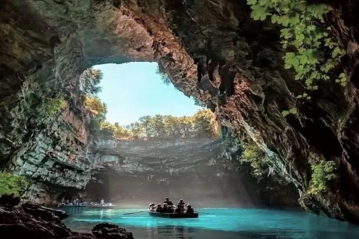 Des touristes en barque explorent le lac ensoleillé de la grotte de Melissani.