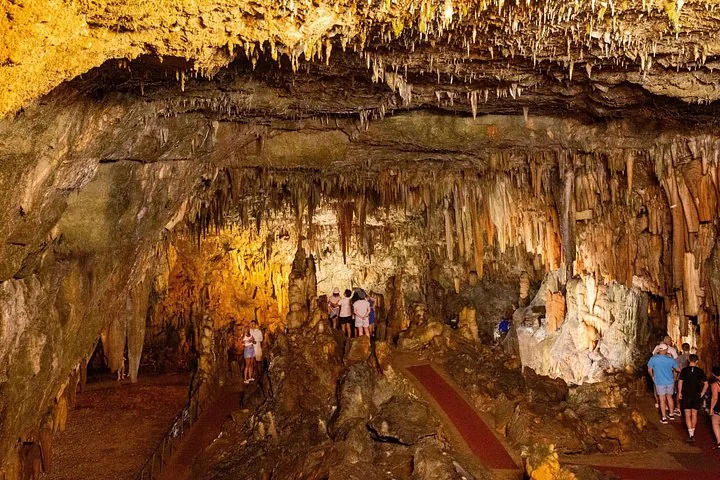 Des visiteurs marchent le long du sentier éclairé à l'intérieur de la grotte de Drogarati.