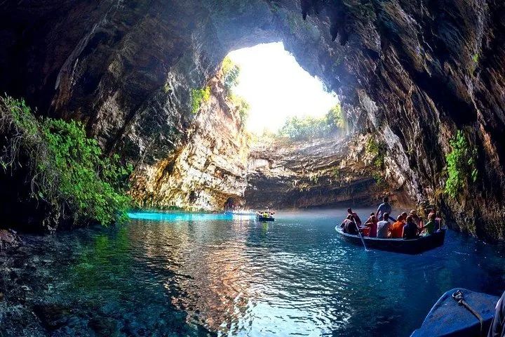Bote lleno de visitantes maravillados con las aguas iluminadas por el sol de la Cueva Melissani.